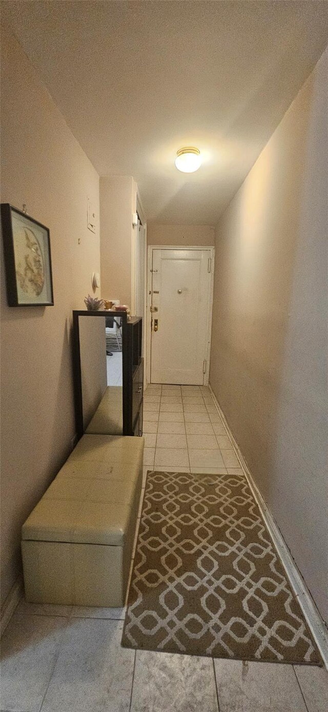 hallway featuring baseboards and light tile patterned floors