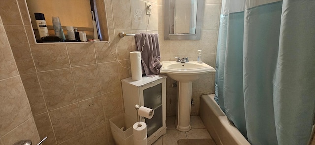bathroom featuring tile walls, tile patterned flooring, shower / tub combo, and a sink