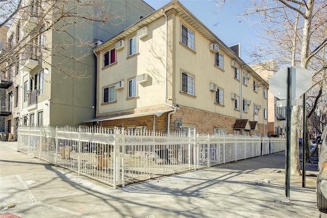 view of property featuring a wall mounted AC, fence private yard, and a wall mounted air conditioner