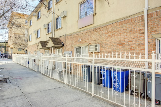 view of building exterior featuring fence and a wall mounted air conditioner