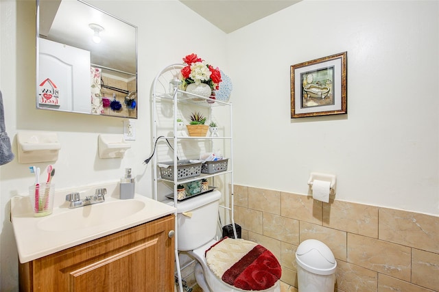 full bath with tile walls, a wainscoted wall, vanity, and toilet
