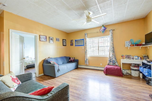 living area with baseboards, ceiling fan, wood finished floors, and baseboard heating