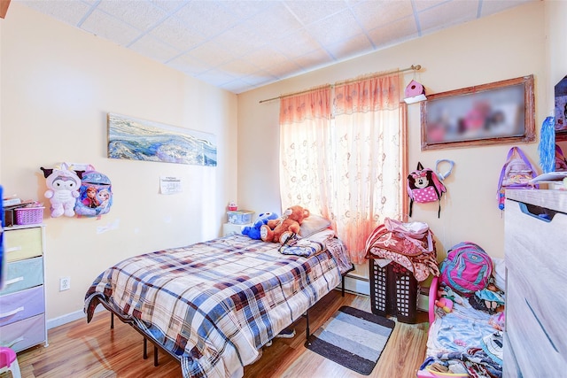 bedroom with wood finished floors and a baseboard radiator