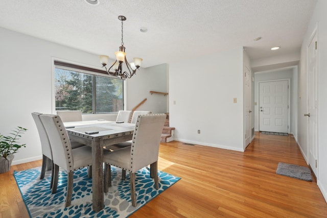 dining space with a textured ceiling, baseboards, light wood finished floors, a notable chandelier, and recessed lighting