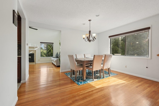 dining space featuring a textured ceiling, a chandelier, a healthy amount of sunlight, and light wood-type flooring