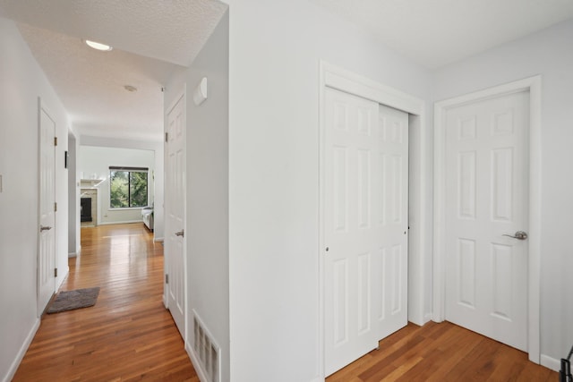 hallway featuring baseboards, wood finished floors, and visible vents