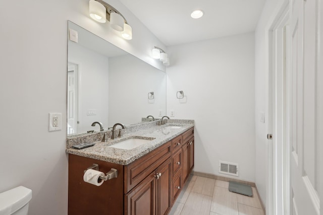 bathroom with a sink, toilet, double vanity, and visible vents