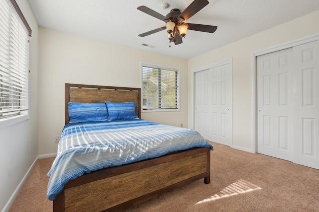 bedroom with baseboards, two closets, carpet flooring, and visible vents