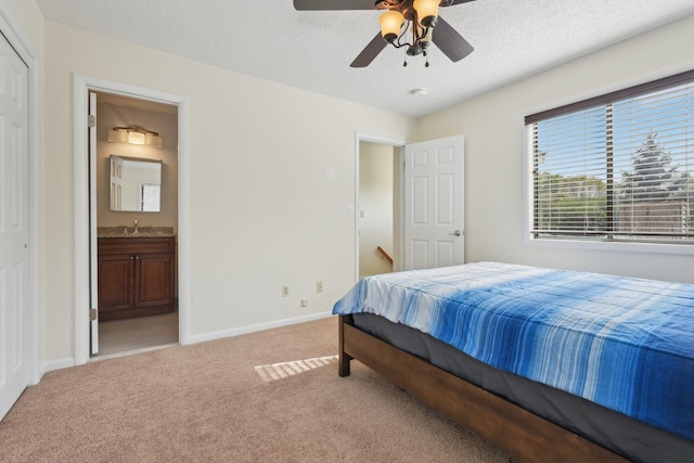 carpeted bedroom featuring ceiling fan, a sink, ensuite bath, a textured ceiling, and baseboards