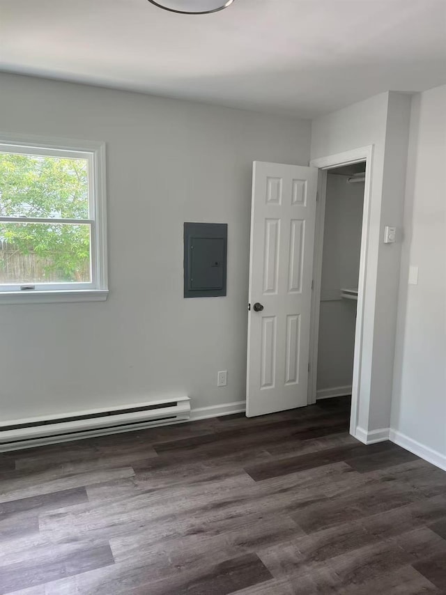 47 Ontario St, Port Jefferson Station, NY 11776 - unfurnished bedroom featuring baseboards, a baseboard radiator, dark wood finished floors, and electric panel