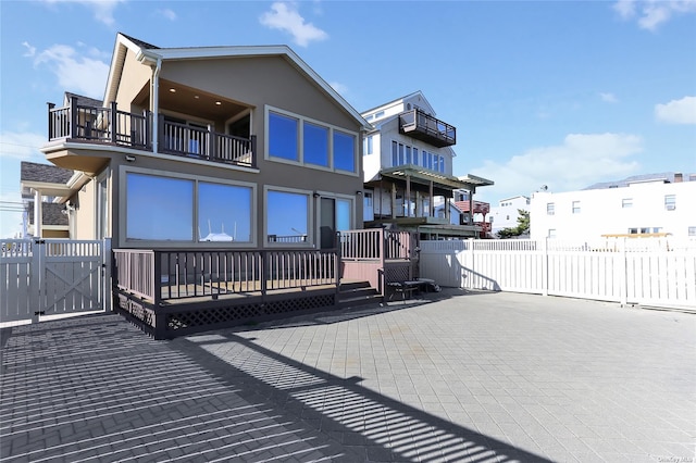 rear view of property with fence, a patio, stucco siding, and a balcony