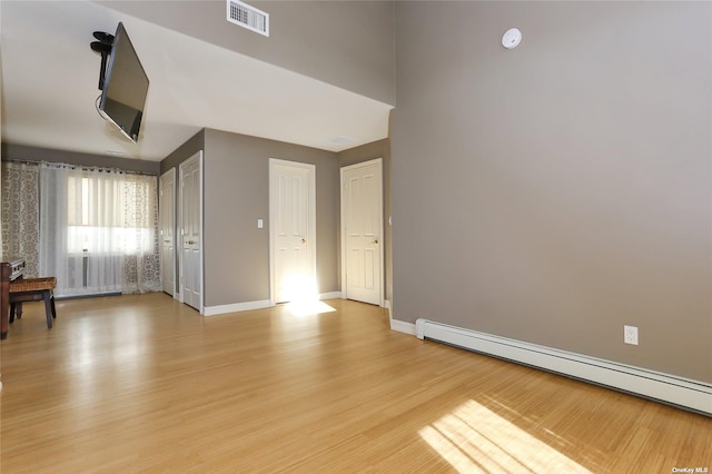 interior space with baseboards, visible vents, light wood finished floors, and a baseboard radiator