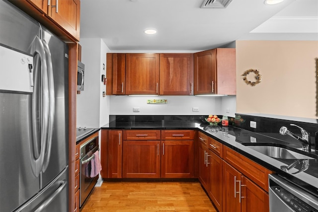 kitchen with appliances with stainless steel finishes, a sink, brown cabinetry, recessed lighting, and light wood-type flooring