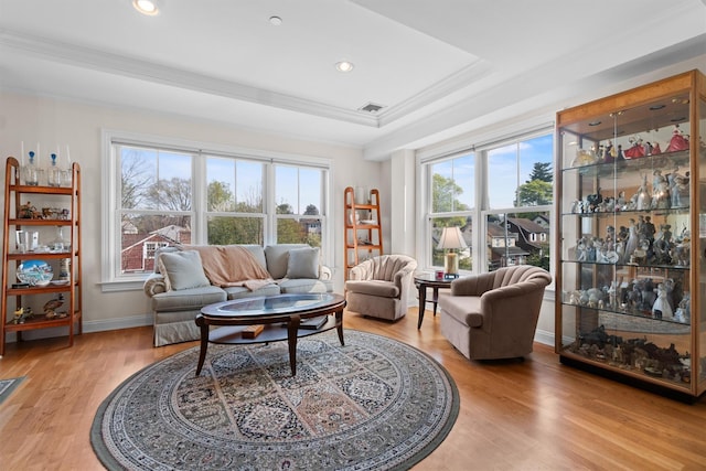sitting room featuring a raised ceiling, ornamental molding, light wood finished floors, and visible vents