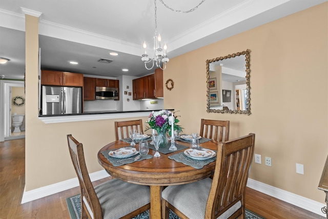 dining room featuring crown molding, baseboards, visible vents, and wood finished floors