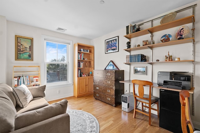 living area featuring visible vents, light wood finished floors, and baseboards