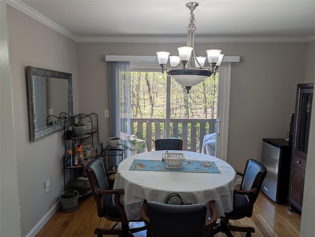 dining space with crown molding, baseboards, a notable chandelier, and wood finished floors