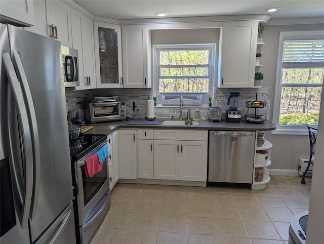kitchen with dark countertops, appliances with stainless steel finishes, a sink, and a toaster
