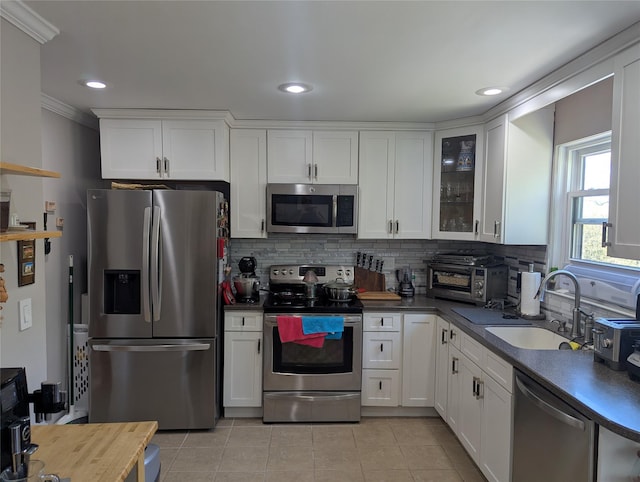 kitchen featuring a sink, stainless steel appliances, white cabinetry, decorative backsplash, and light tile patterned floors