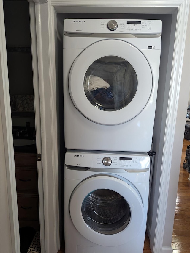 washroom featuring laundry area, stacked washer and dryer, and wood finished floors