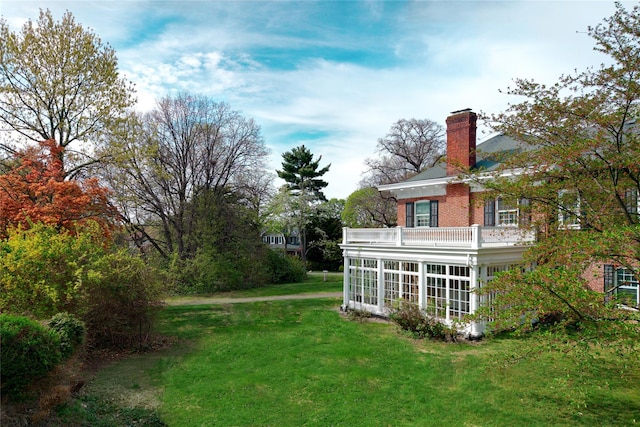 view of yard featuring a sunroom and a balcony