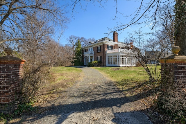 view of front of home featuring french doors, a chimney, a front lawn, and a balcony