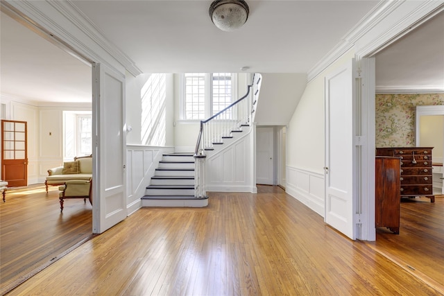 interior space featuring a wainscoted wall, wood-type flooring, a decorative wall, and stairs