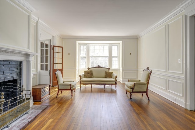 living area featuring ornamental molding, a fireplace, a decorative wall, and dark wood-style flooring