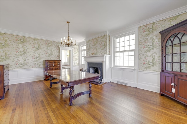 interior space featuring an inviting chandelier, wainscoting, a fireplace, and wallpapered walls