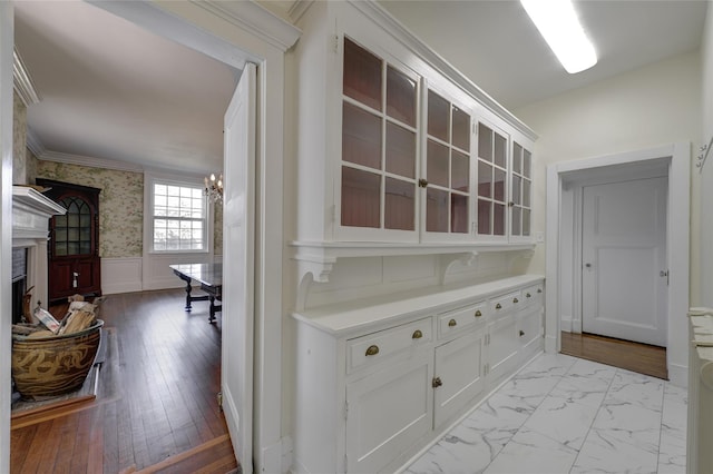 hallway with ornamental molding, wainscoting, and a chandelier