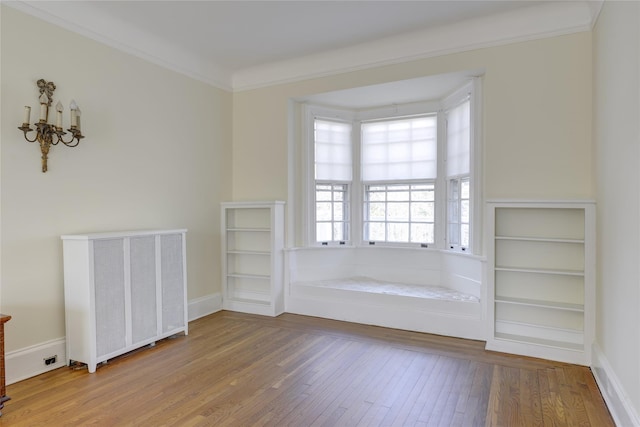 spare room featuring baseboards, a chandelier, ornamental molding, and hardwood / wood-style flooring