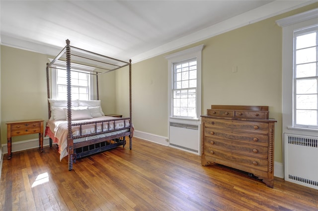 bedroom with baseboards, radiator, and hardwood / wood-style floors