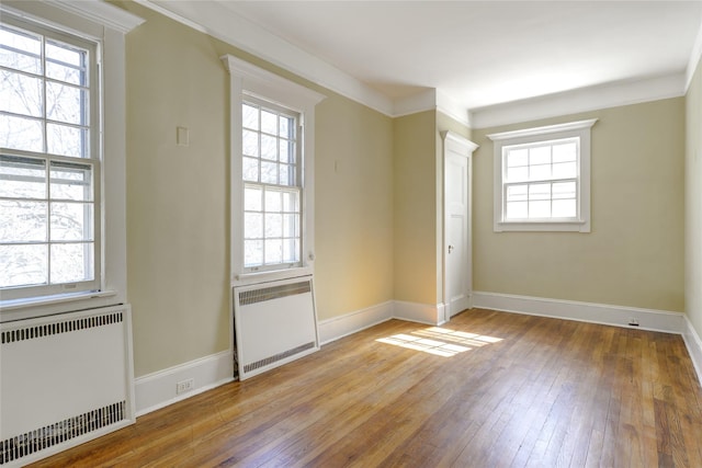 unfurnished room featuring plenty of natural light, radiator heating unit, and hardwood / wood-style floors