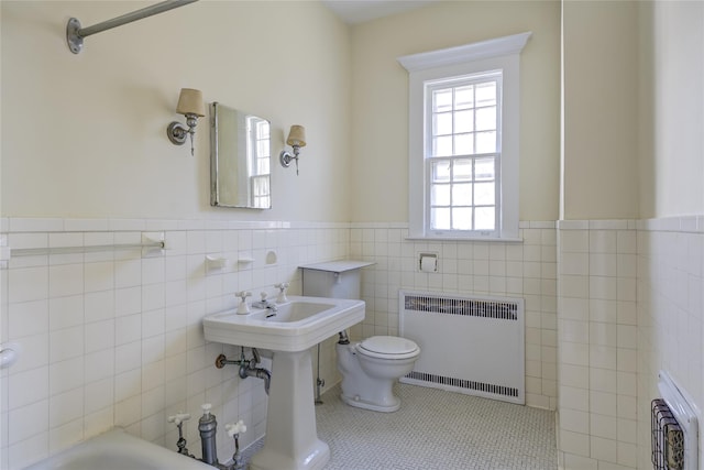full bathroom with tile walls, tile patterned flooring, wainscoting, toilet, and radiator heating unit
