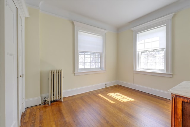 unfurnished room with radiator heating unit, hardwood / wood-style flooring, and a wealth of natural light
