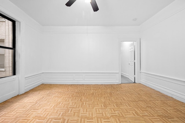 empty room with ceiling fan and a wainscoted wall