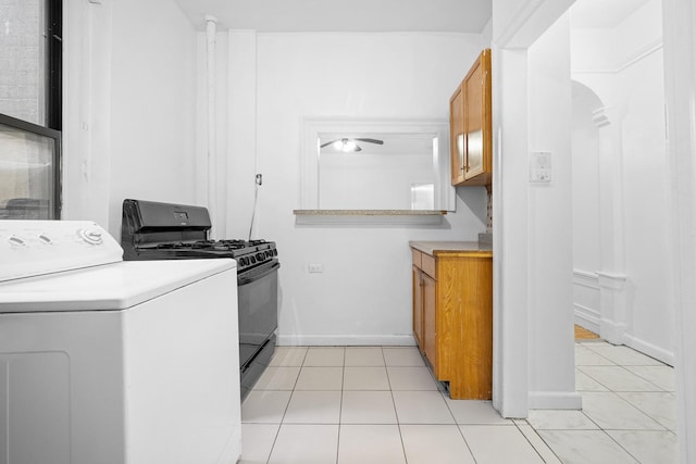 kitchen featuring washer / clothes dryer, black gas range oven, light countertops, and light tile patterned floors