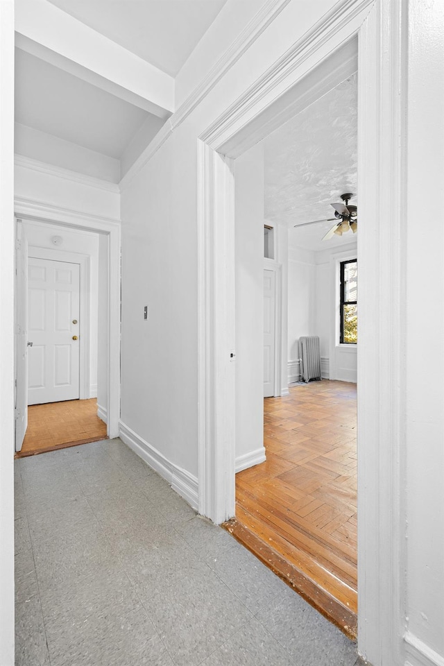 hallway featuring radiator heating unit, baseboards, and tile patterned floors
