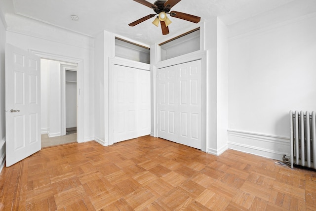 unfurnished bedroom with radiator, baseboards, and a ceiling fan