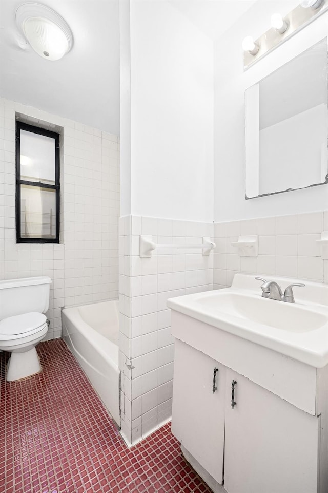 full bath featuring tile walls, toilet, a tub, vanity, and wainscoting