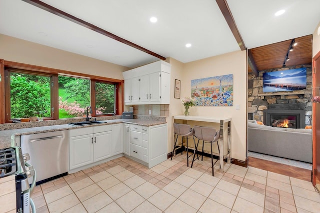 38A Claremont Rd, Scarsdale, NY 10583 - kitchen with a sink, stainless steel appliances, a stone fireplace, light countertops, and white cabinetry