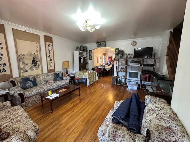living room with arched walkways, wood finished floors, stairway, an inviting chandelier, and ornamental molding