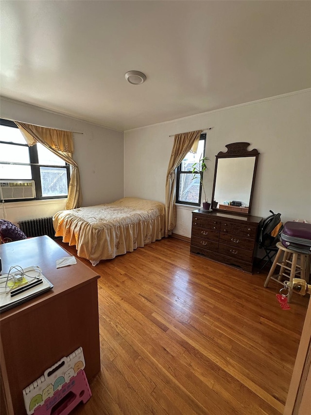 bedroom featuring radiator heating unit, cooling unit, and wood finished floors