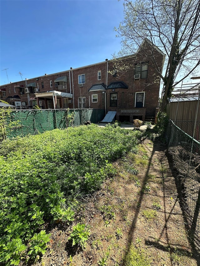 rear view of property with brick siding and fence
