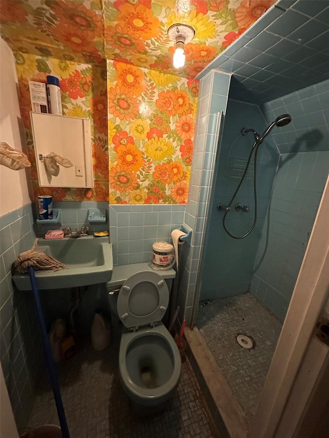 bathroom featuring wallpapered walls, wainscoting, a shower stall, and tile walls