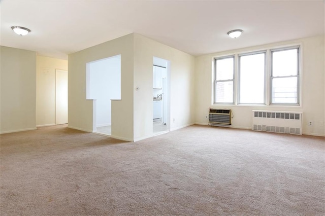 empty room with baseboards, radiator heating unit, heating unit, and carpet