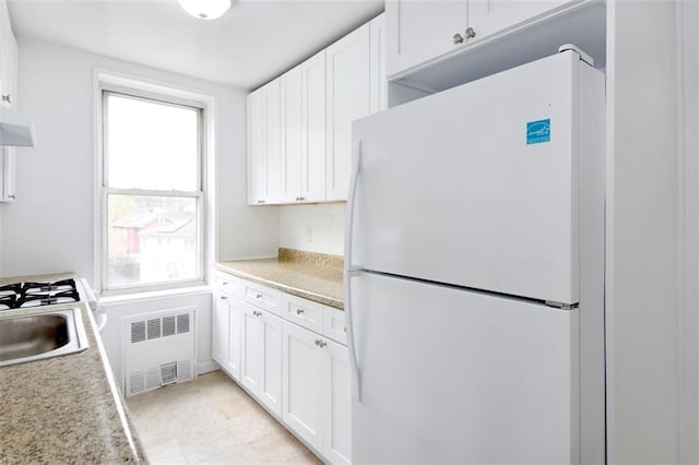 kitchen featuring freestanding refrigerator, white cabinetry, light countertops, and radiator