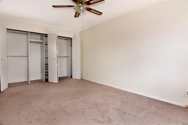 unfurnished bedroom featuring carpet, two closets, baseboards, and a ceiling fan