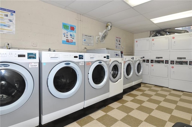 shared laundry area featuring stacked washer / drying machine, light floors, concrete block wall, and washer and dryer