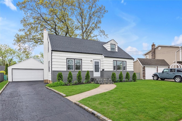 cape cod home featuring a front yard, an outbuilding, a shingled roof, and a detached garage